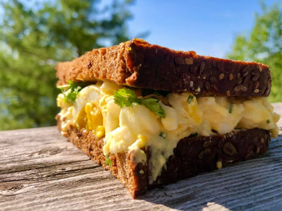 egg salad sandwich on dark rye with hard boiled egg tucked in