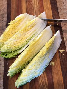 napa cabbage on cutting board being cut