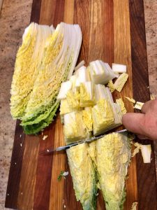 napa cabbage on cutting board being chopped