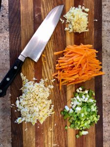 minced garlic, onion, ginger, and carrot on cutting board