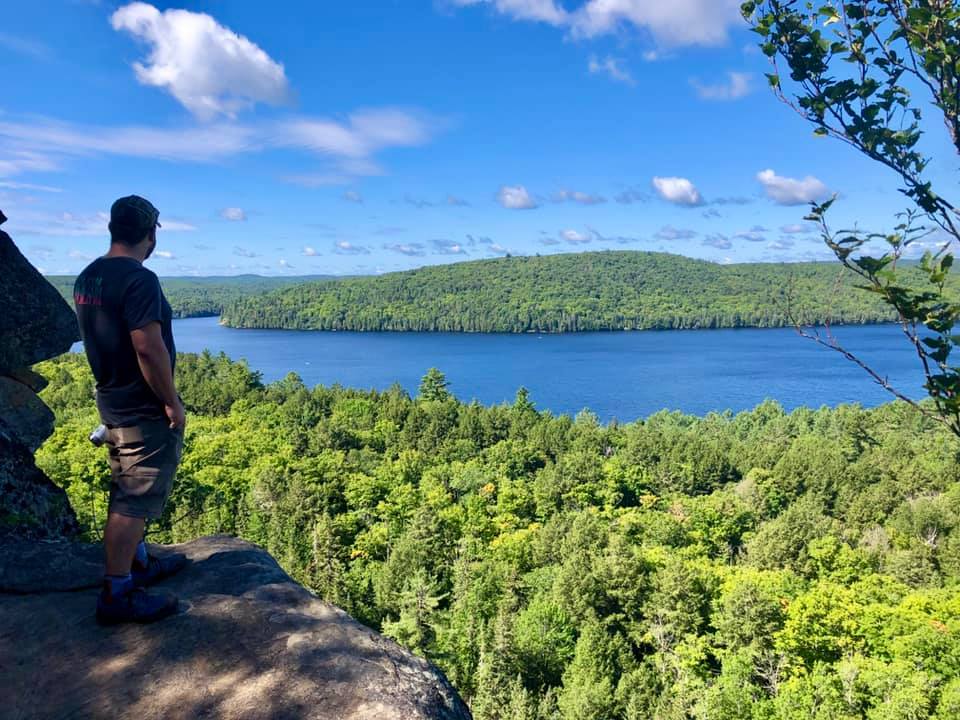 man overlooking a forest and river from a high rock