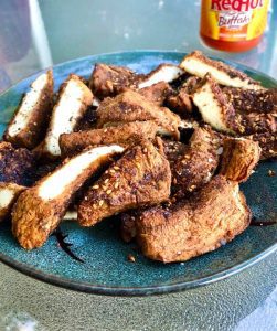 grilled slices of puffball mushroom coated in za'atar spice on a blue plate