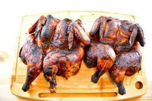 Two whole roasted chickens in a red sauce