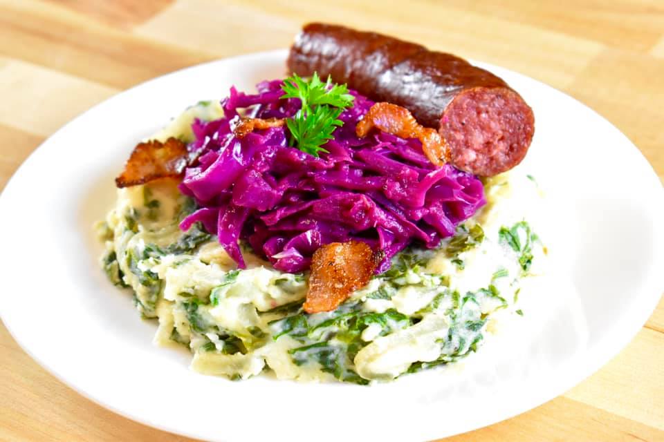 mashed potatoes mixed with green kale, with braised red cabbage and a smoked sausage on top