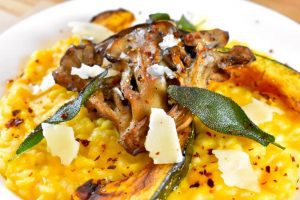 orange risotto topped with a roasted maitake mushroom