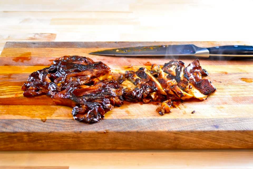 maitake mushroom slathered in barbecue sauce being cut on a cutting board