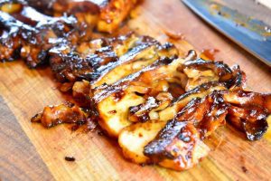 barbecued maitake being sliced on a cutting board