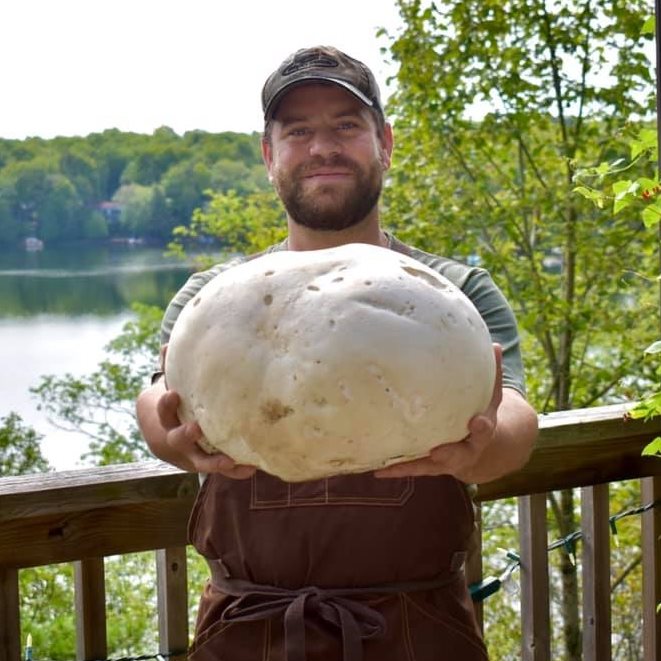 a man holding a very large puffball mushroom
