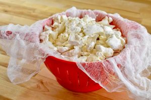 broken apart mushrooms in a colander lined with cheesecloth