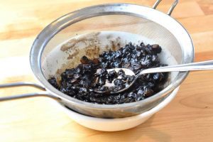 nannyberries being passed through a sieve 