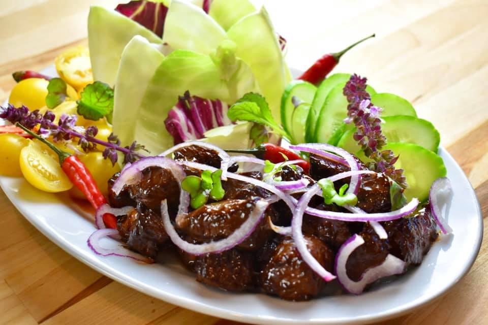 plate of Vietnamese shaking goose breast with colourful vegetables and herbs