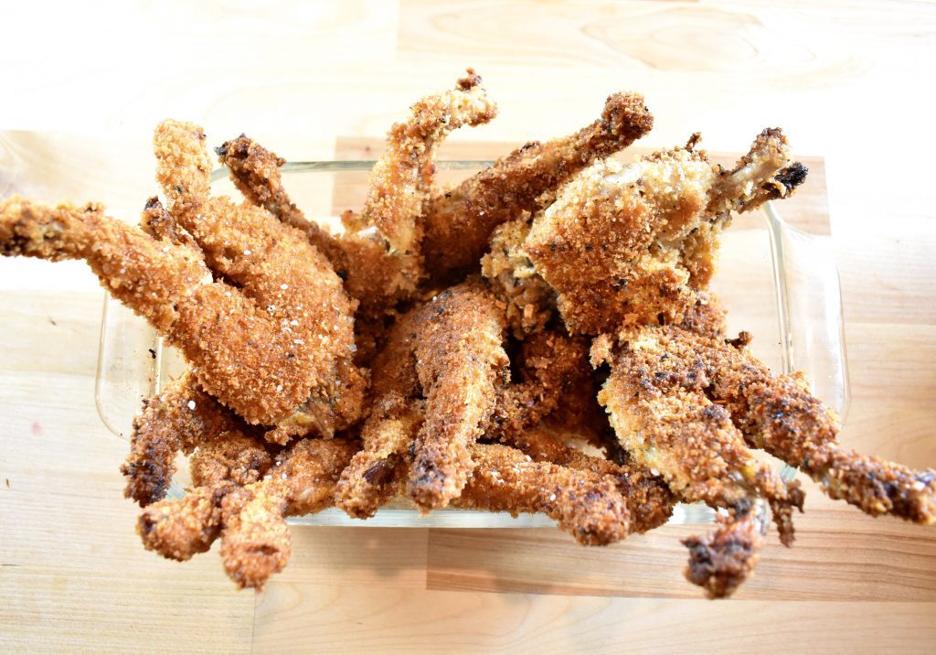 a rectangular glass container full of golden fried frogs legs