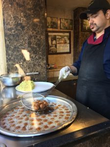 man frying falafel in a large cooking vessel